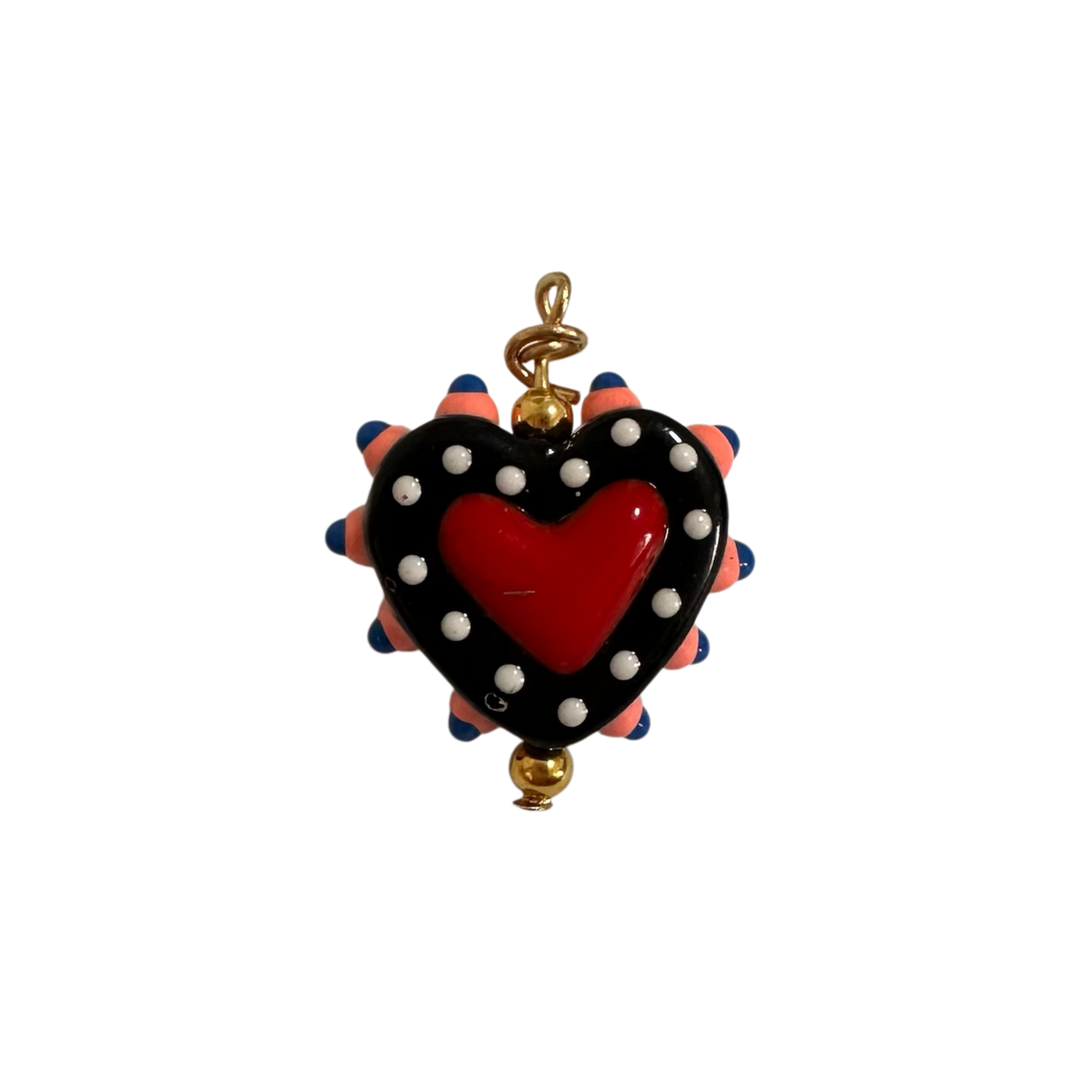 A heart-shaped pendant charm featuring a glossy red heart in the center, surrounded by a black border with white polka dots and pink and blue spikes.