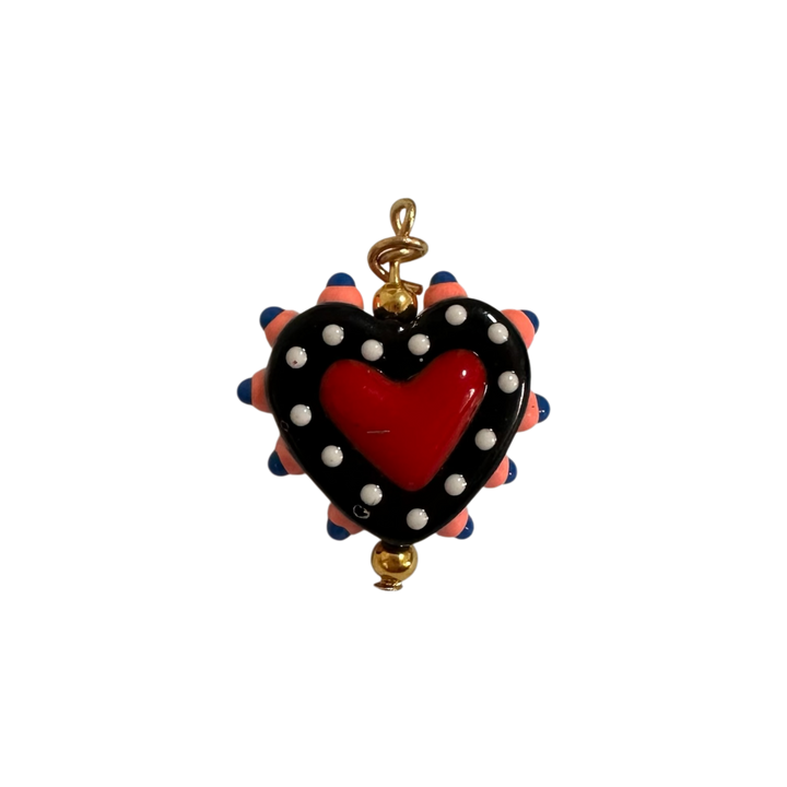 A heart-shaped pendant charm featuring a glossy red heart in the center, surrounded by a black border with white polka dots and pink and blue spikes.