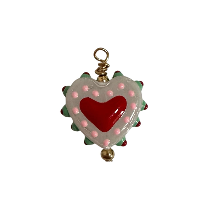 A heart-shaped charm with a glossy red heart in the center, surrounded by a white border with pink dots and green spikes.