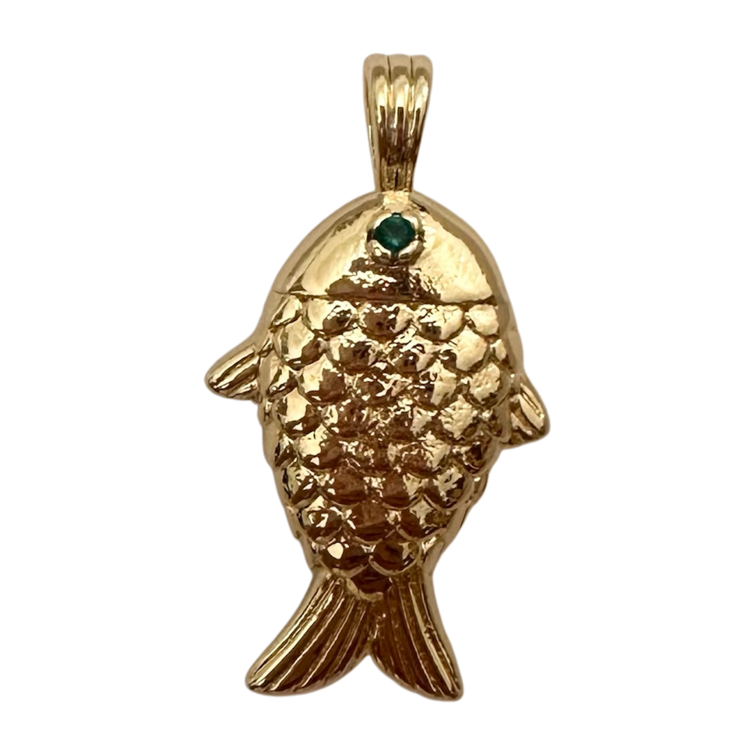 A gold fish-shaped pendant with a textured scale pattern and a small green gemstone accent in the eye, shown on a plain white background.