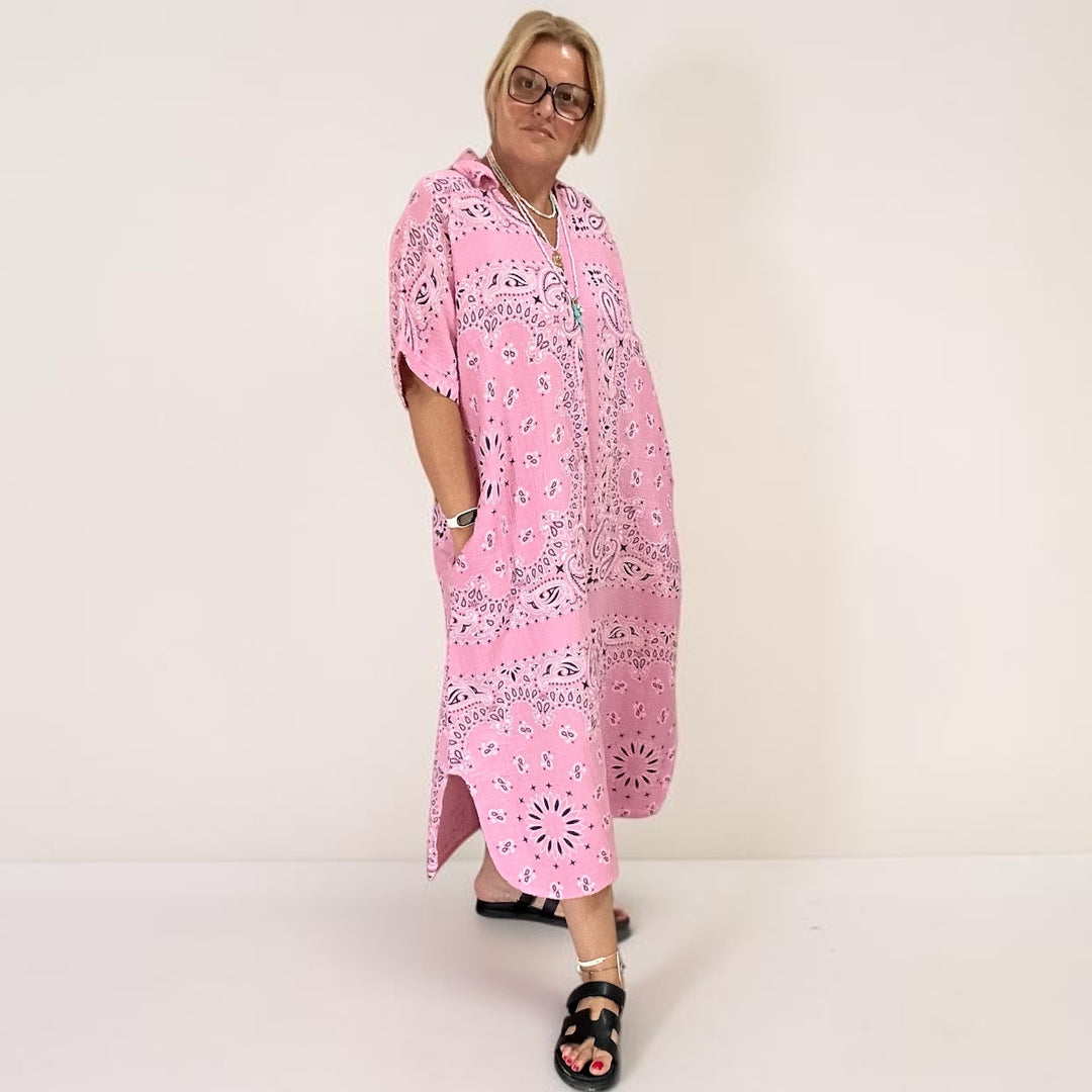 A woman modeling a pink hooded kaftan dress in cotton gauze with a white and navy paisley bandana pattern, 