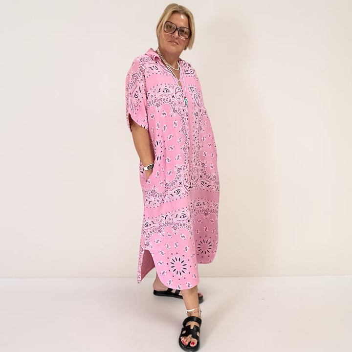 A woman modeling a pink hooded kaftan dress in cotton gauze with a white and navy paisley bandana pattern, 